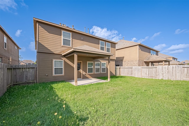 rear view of house with a fenced backyard, a yard, and a patio area