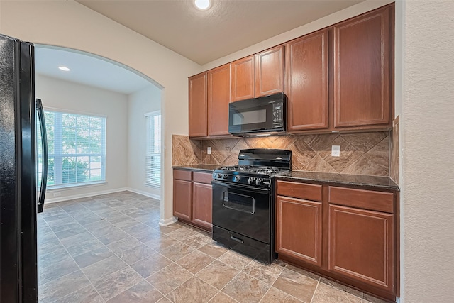 kitchen featuring arched walkways, tasteful backsplash, black appliances, stone tile flooring, and recessed lighting