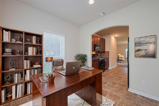 office area featuring arched walkways, baseboards, and visible vents