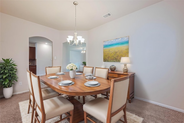 dining area with an inviting chandelier, light carpet, arched walkways, baseboards, and visible vents