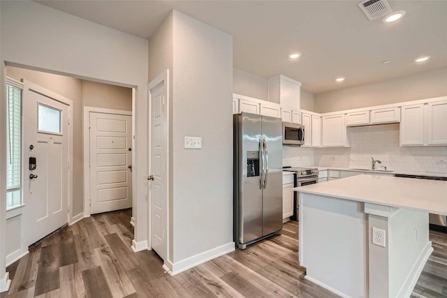 kitchen featuring backsplash, visible vents, appliances with stainless steel finishes, a sink, and light countertops