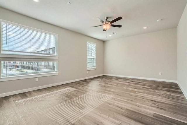 spare room featuring a ceiling fan, baseboards, a wealth of natural light, and wood finished floors