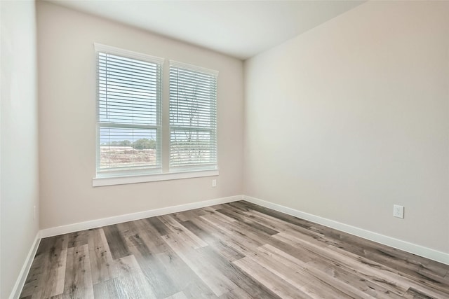 unfurnished room with baseboards and wood finished floors