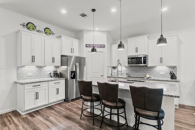 kitchen featuring visible vents, decorative backsplash, wood finished floors, a sink, and stainless steel appliances
