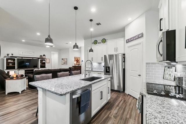 kitchen featuring visible vents, tasteful backsplash, a sink, open floor plan, and stainless steel appliances