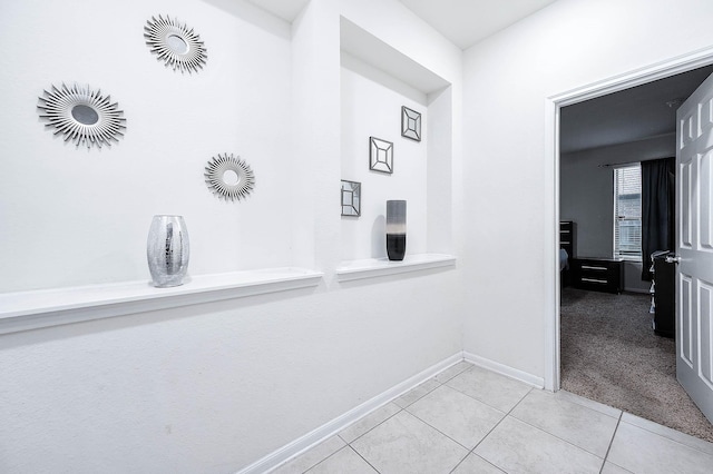 hallway featuring tile patterned floors, baseboards, and carpet