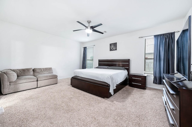 bedroom featuring ceiling fan, light colored carpet, multiple windows, and baseboards