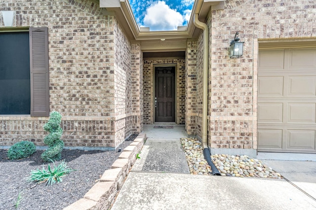 view of exterior entry featuring brick siding and a garage