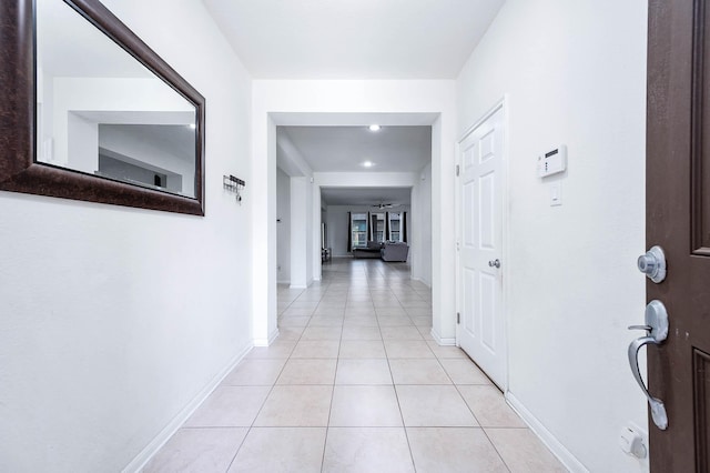 corridor featuring light tile patterned floors, baseboards, and recessed lighting