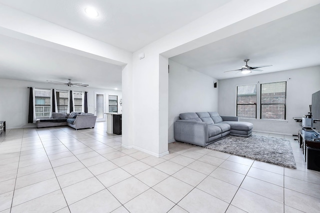 living area with baseboards, a ceiling fan, and light tile patterned floors