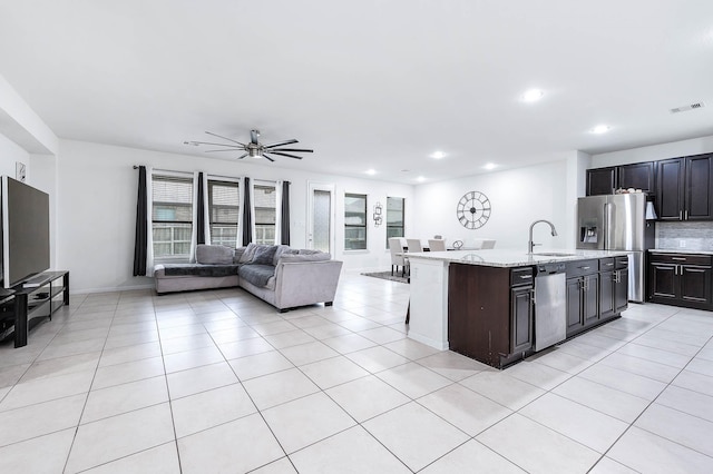kitchen with visible vents, a ceiling fan, open floor plan, a sink, and stainless steel appliances