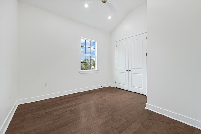 unfurnished bedroom featuring baseboards, dark wood finished floors, and lofted ceiling