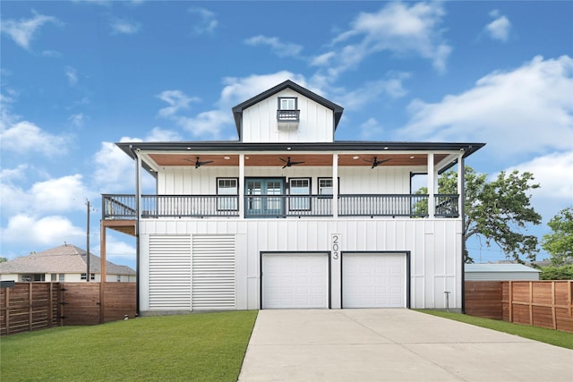 view of front facade featuring fence, board and batten siding, a front yard, a ceiling fan, and driveway