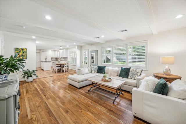 living room featuring recessed lighting, beamed ceiling, visible vents, and light wood-type flooring