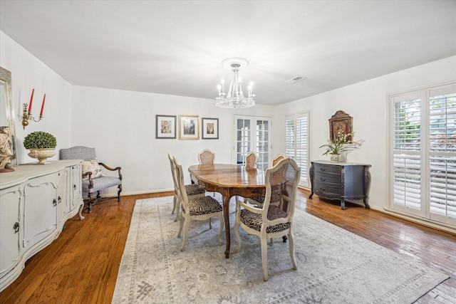 dining space featuring an inviting chandelier, wood finished floors, and visible vents