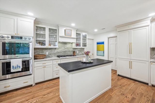 kitchen featuring light wood-style flooring, white cabinets, tasteful backsplash, and stainless steel appliances