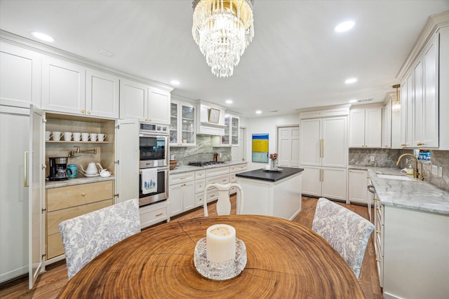 kitchen featuring a center island, stainless steel double oven, gas stovetop, a sink, and backsplash