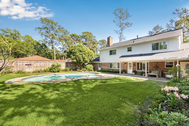 rear view of house featuring brick siding, a fenced backyard, a chimney, a patio, and a yard