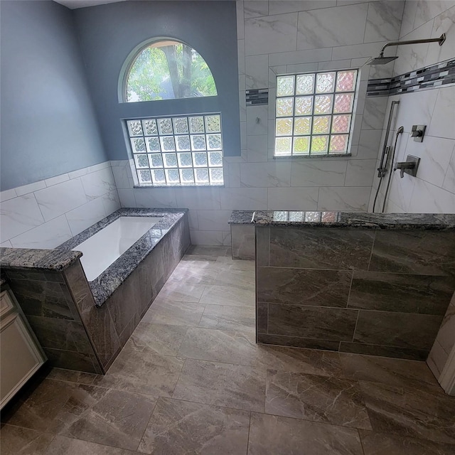 bathroom with walk in shower, tile walls, and a garden tub