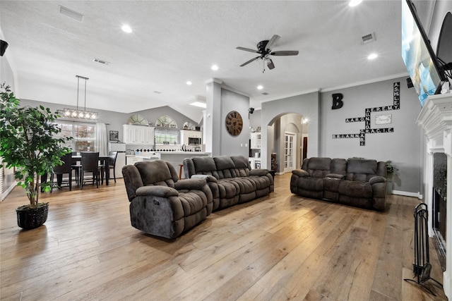 living area featuring ceiling fan, light wood-style floors, a fireplace, arched walkways, and visible vents