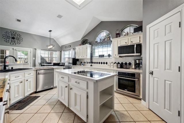 kitchen with appliances with stainless steel finishes, a sink, light countertops, lofted ceiling, and white cabinetry