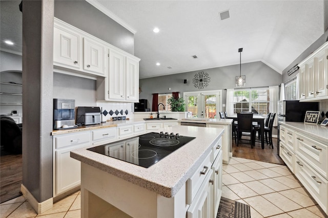 kitchen featuring a center island, black electric cooktop, a sink, light tile patterned floors, and a peninsula