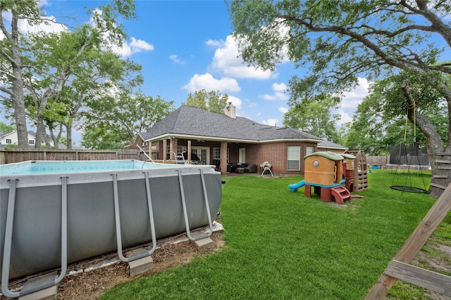 view of pool featuring a fenced backyard, a fenced in pool, a playground, a lawn, and a trampoline