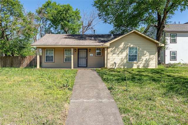 view of front of home with a shingled roof, fence, covered porch, and a front yard