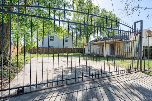 view of gate with fence private yard and a lawn