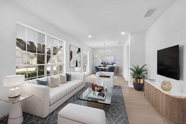 living area with an inviting chandelier, light wood finished floors, plenty of natural light, and visible vents