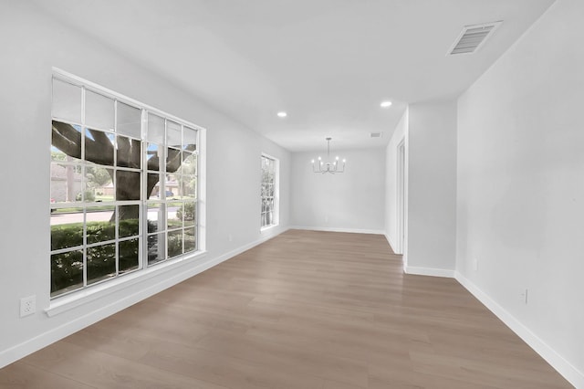 unfurnished room with visible vents, recessed lighting, wood finished floors, and a chandelier