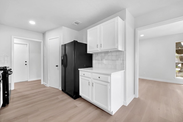 kitchen with visible vents, light countertops, black appliances, light wood finished floors, and white cabinetry