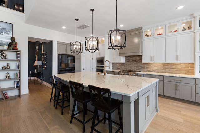 208 S Empress Green Pl, Montgomery, TX 77316 - kitchen with an inviting chandelier, stainless steel appliances, custom range hood, tasteful backsplash, and visible vents