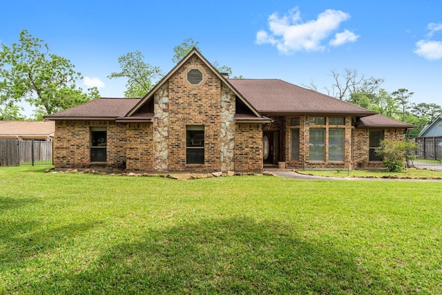 view of front of property featuring fence, a shingled roof, a front lawn, and brick siding