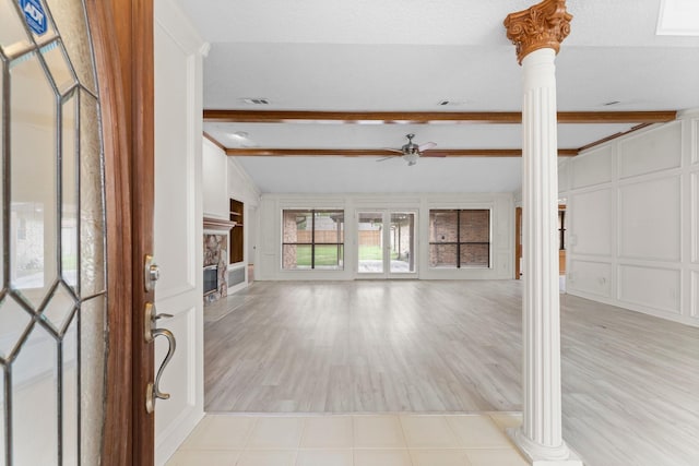 entrance foyer with decorative columns, a decorative wall, a fireplace, ceiling fan, and vaulted ceiling with beams