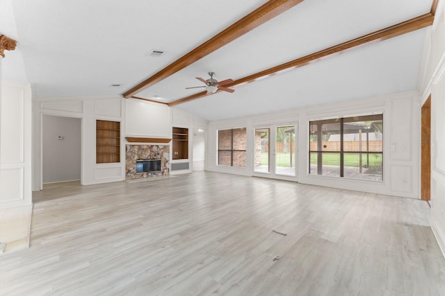 unfurnished living room with ceiling fan, a stone fireplace, visible vents, built in shelves, and lofted ceiling with beams