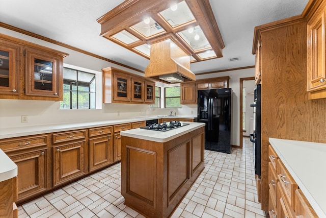 kitchen featuring brick patterned floor, brown cabinetry, a sink, and black fridge with ice dispenser