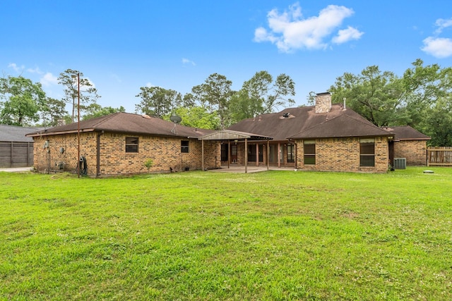 back of property with central AC, fence, a patio, brick siding, and a yard