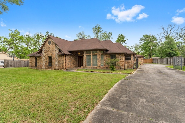 view of front facade featuring fence, a front lawn, brick siding, a chimney, and concrete driveway