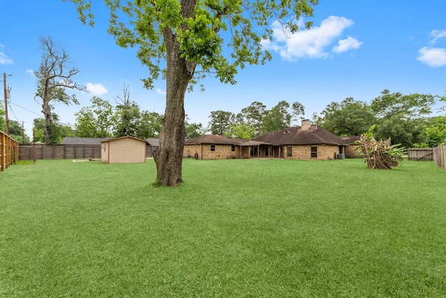 view of yard with an outdoor structure, a fenced backyard, and a storage unit