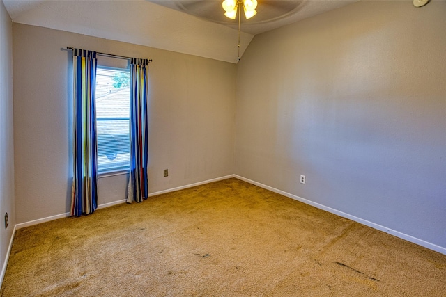 carpeted spare room featuring ceiling fan, baseboards, and vaulted ceiling