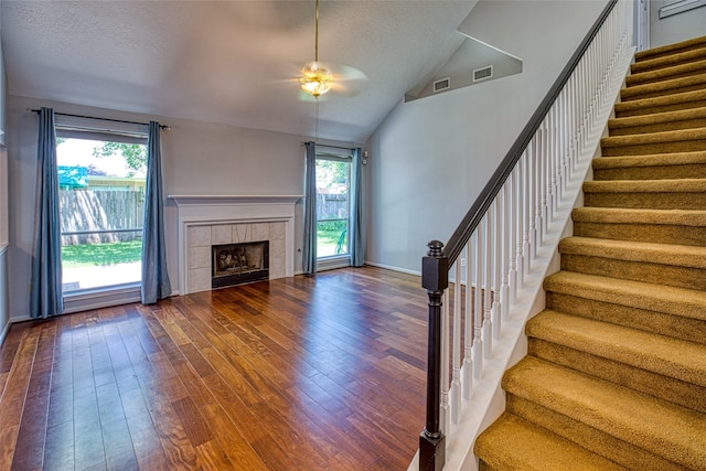 unfurnished living room with a ceiling fan, lofted ceiling, dark wood-style floors, stairway, and plenty of natural light