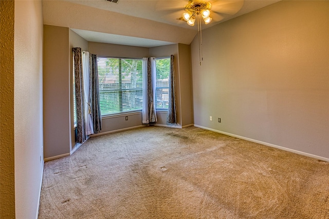 carpeted spare room with a ceiling fan and baseboards