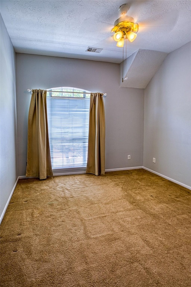 carpeted empty room with a textured ceiling, a ceiling fan, and baseboards