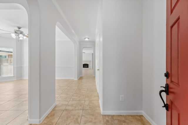foyer entrance featuring baseboards, arched walkways, ceiling fan, and light tile patterned floors