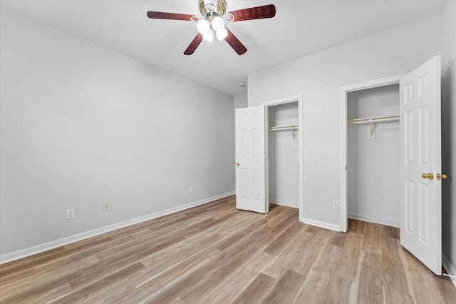 unfurnished bedroom featuring multiple closets, baseboards, a ceiling fan, and light wood finished floors