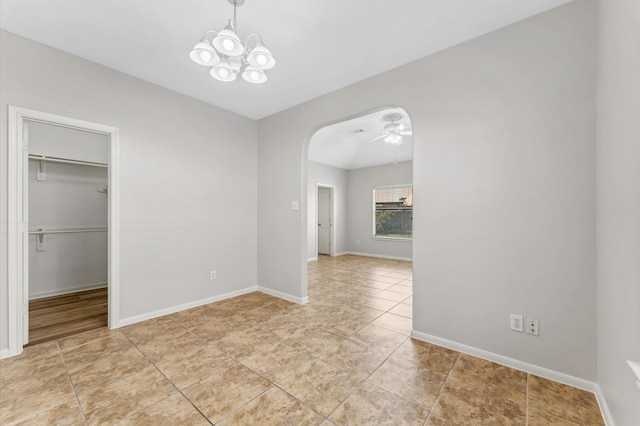 unfurnished dining area featuring arched walkways, baseboards, light tile patterned floors, and ceiling fan with notable chandelier