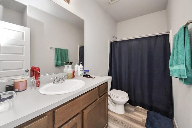 bathroom with vanity, curtained shower, toilet, and wood finished floors