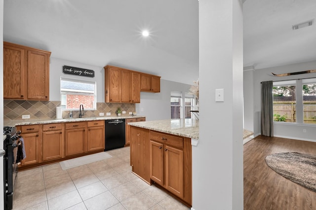 kitchen with visible vents, decorative backsplash, light stone counters, a sink, and black appliances