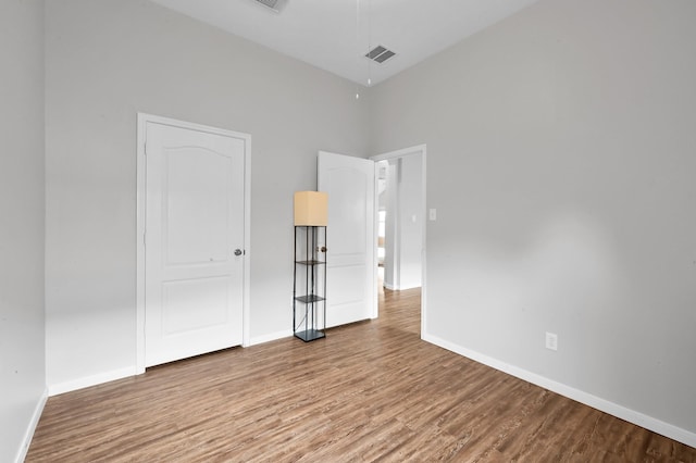 unfurnished bedroom with baseboards, wood finished floors, and visible vents